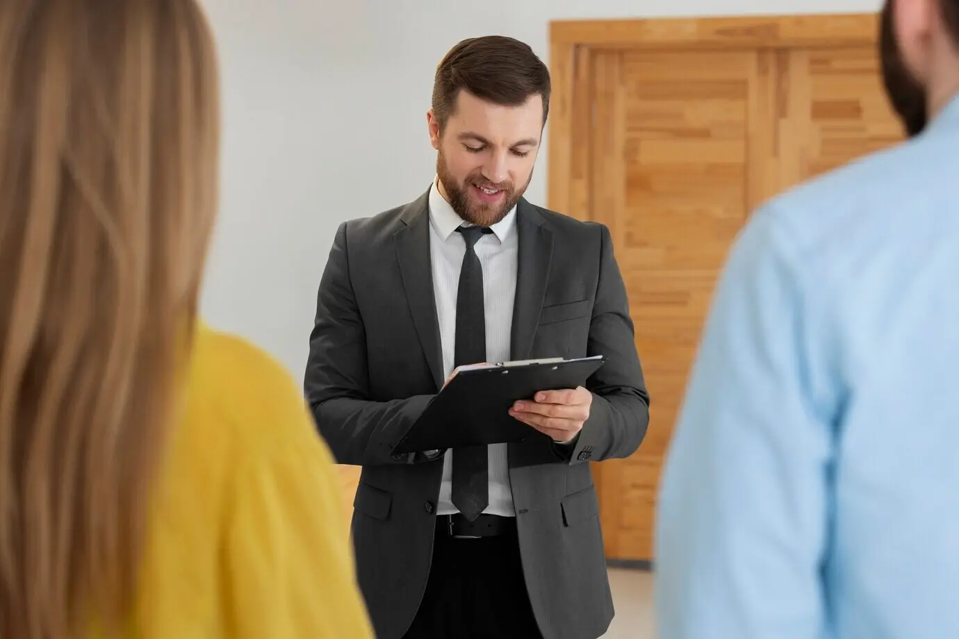 Männlicher Immobilienmakler, der geschäftlich tätig ist und einem potenziellen Käuferpaar ein Haus zeigt.